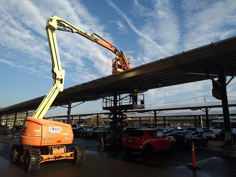 Construction-workers-on-articulating-and-scissor-boom-lifts-working-on-solar-panels-at-a-train-stati